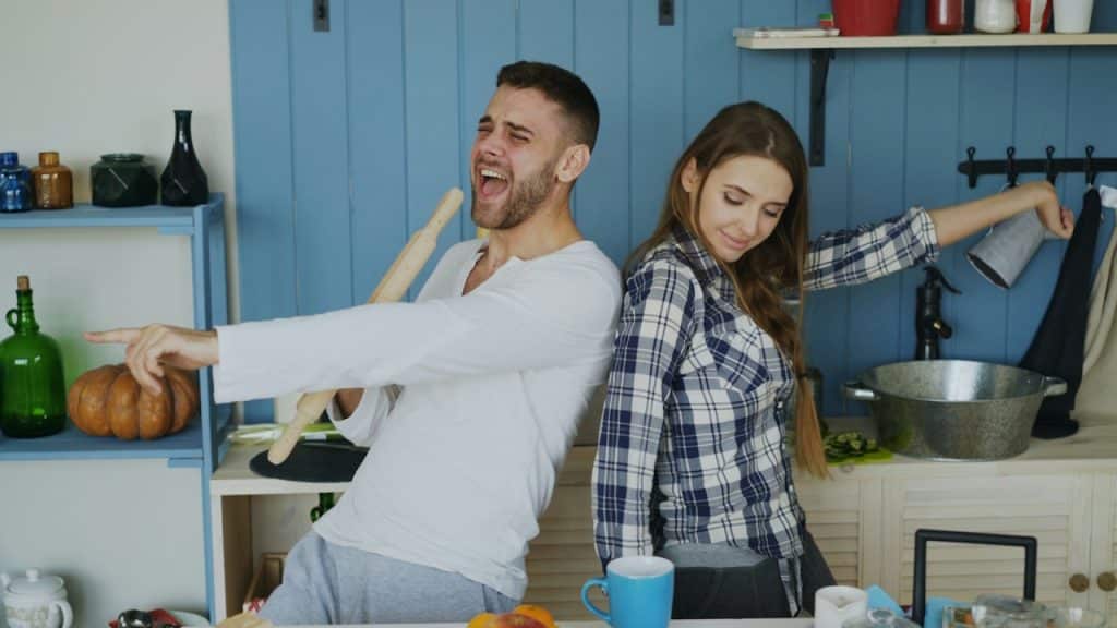 A couple dancing and singing in the kitchen.