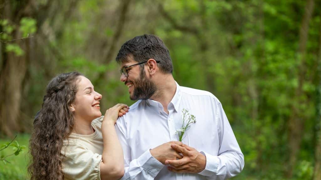 A man and a woman standing in the woods.