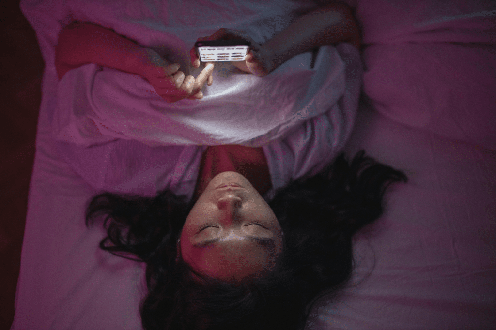 A Woman Lying on Bed and Holding an Iphone