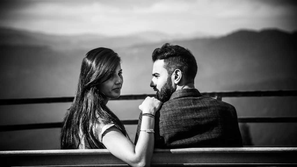 A black and white photo of a couple sitting on a bench.