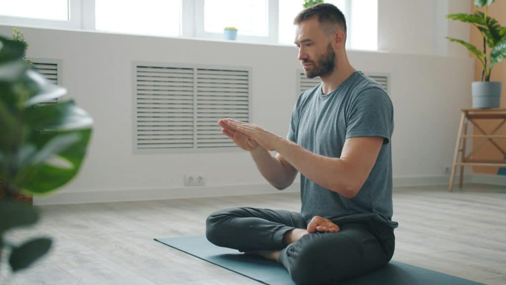 A man meditating in a bright minimalist room.