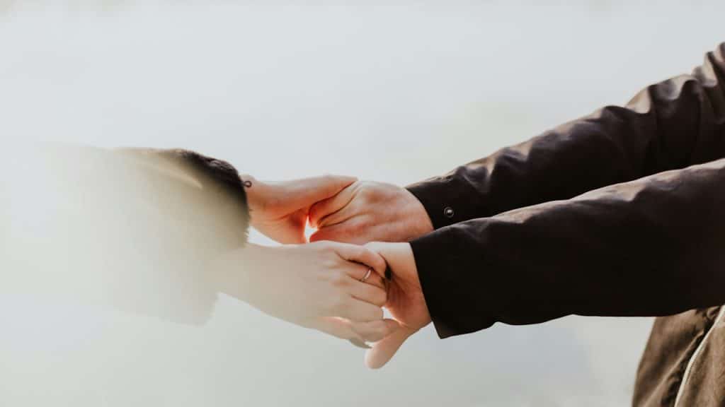 Couple holding hands while standing next to each other.