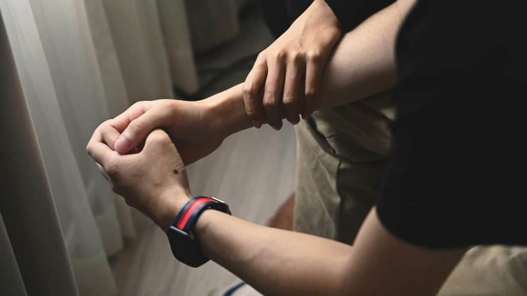 A person holding another person’s wrist gently in a supportive gesture.