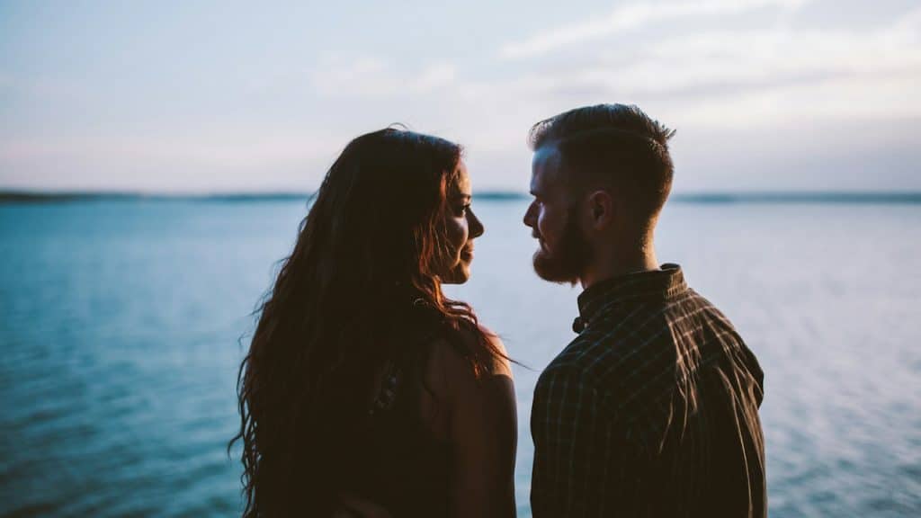 A couple gazing into each other’s eyes in front of the ocean.