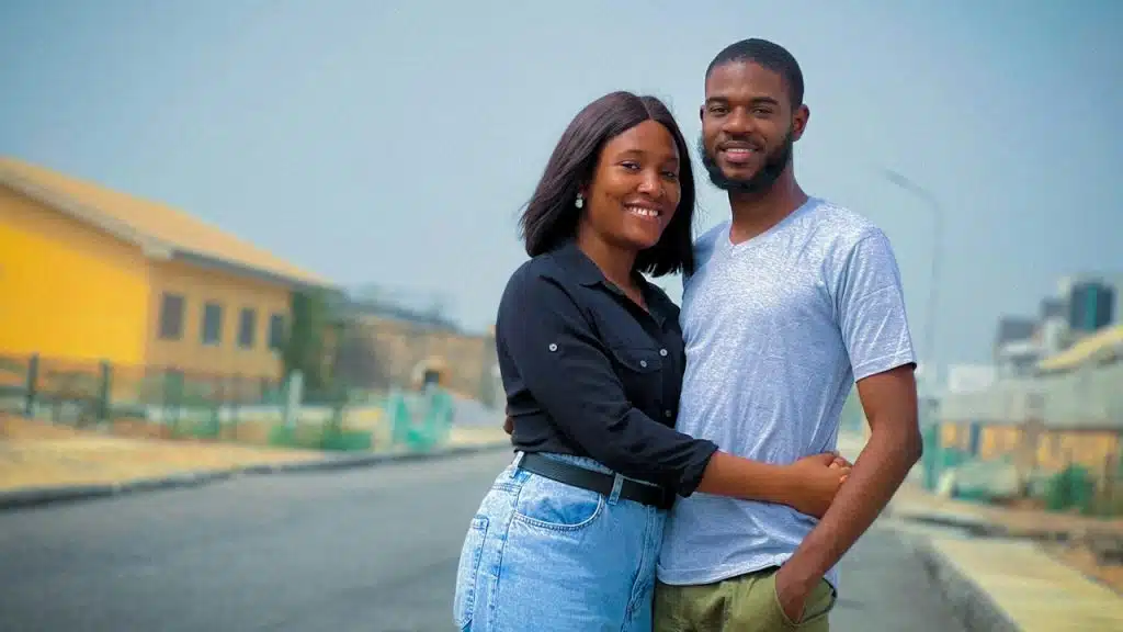 A smiling couple hugging in the street.
