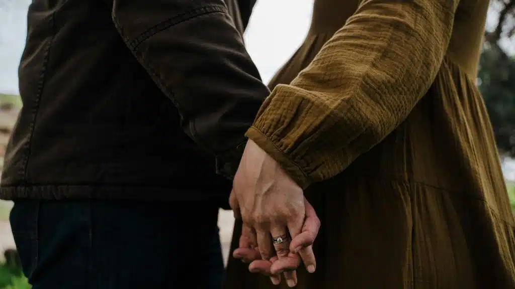 A couple holding hands outdoors.