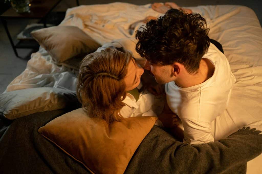 The couple is lying in bed together.