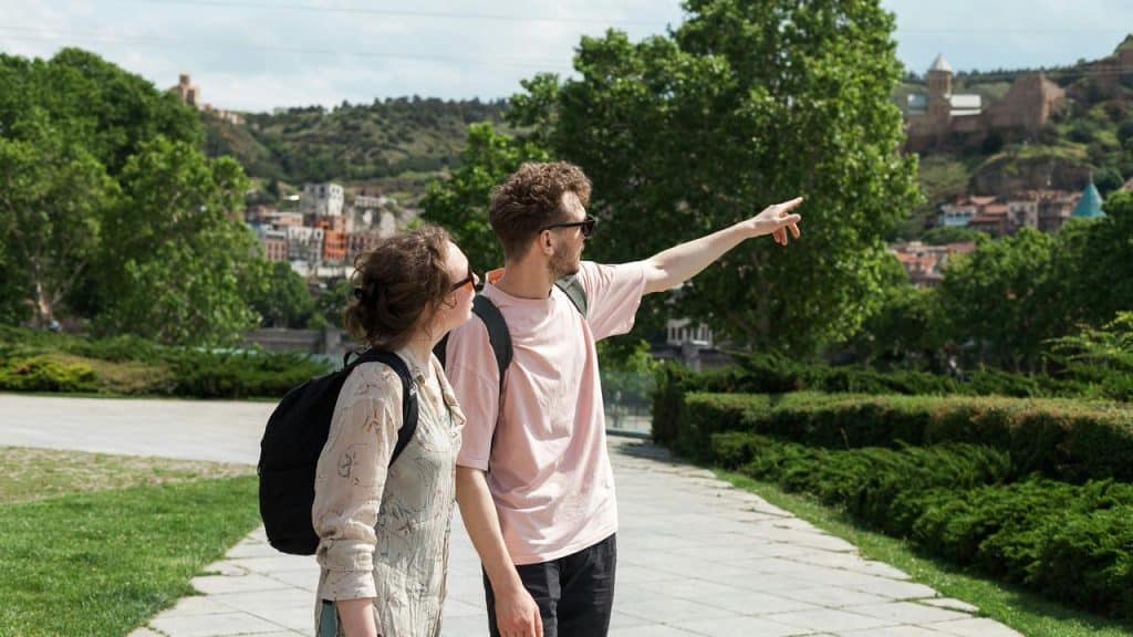 A couple sightseeing outdoors with the man pointing towards a distant view.