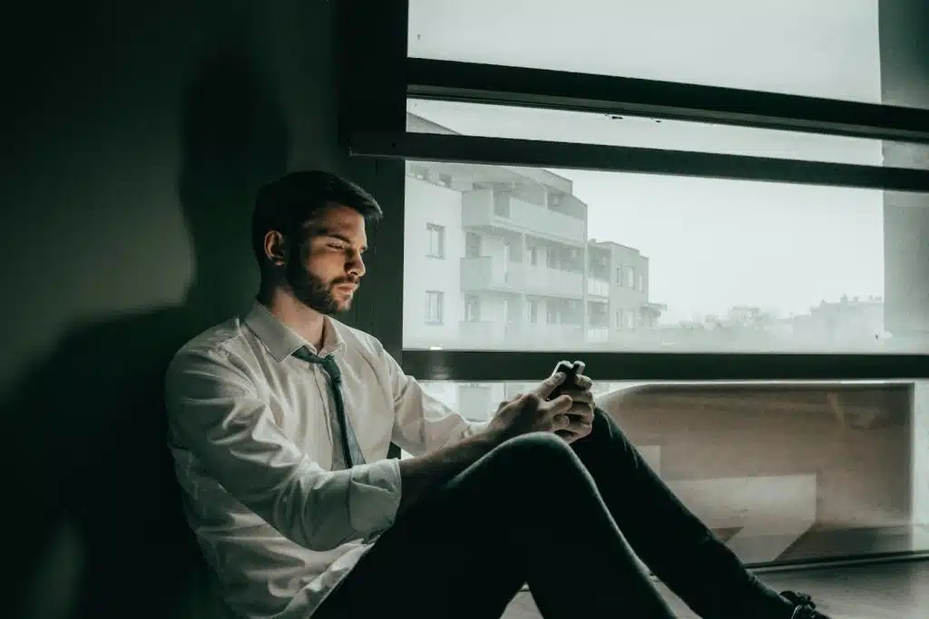 A man sitting near a window looking lonely.