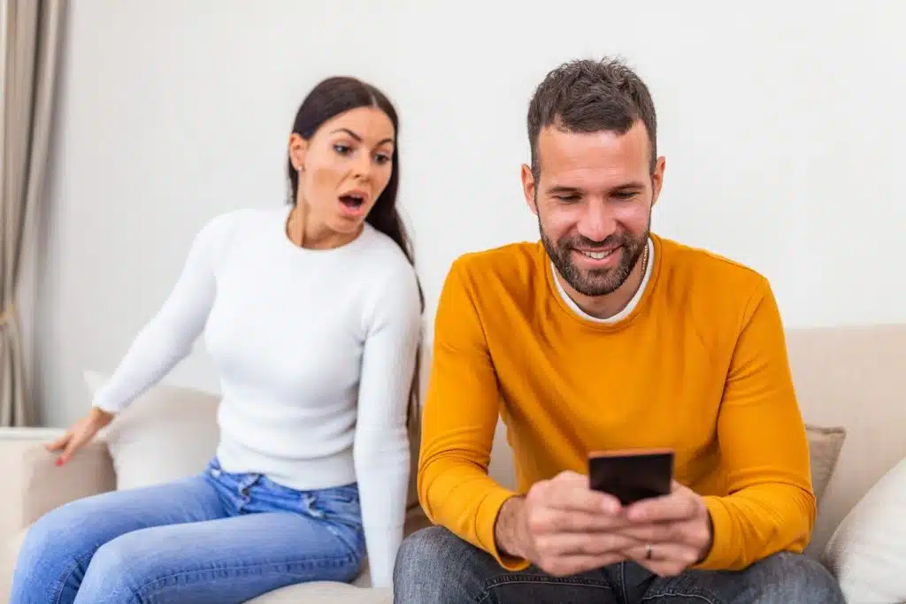 The woman is looking at the man’s phone.