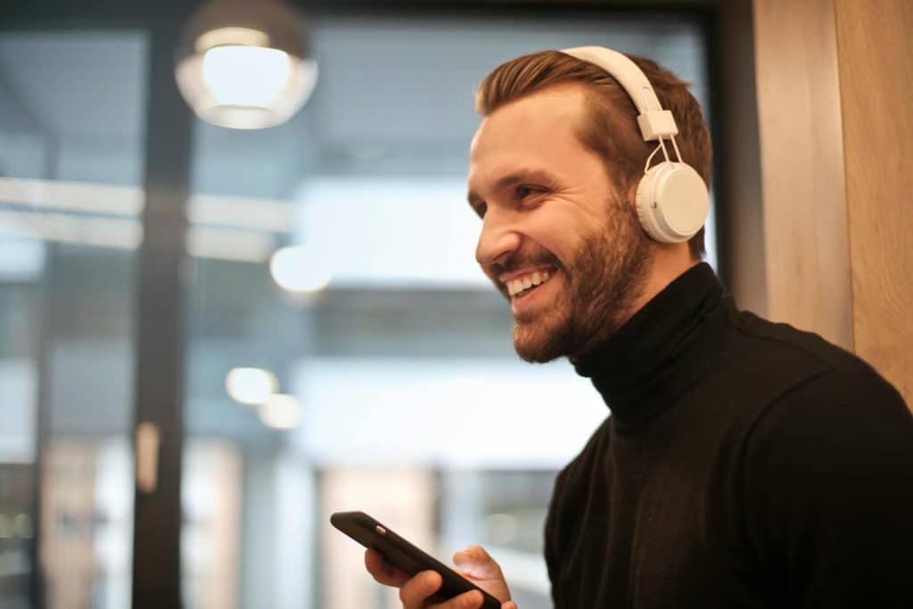 The man is smiling while listening to music.