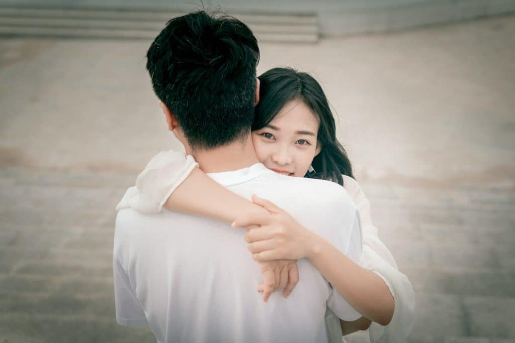 The woman in white is hugging the man.