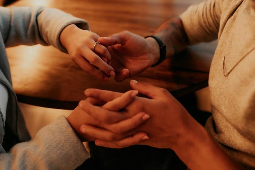 The couple is holding hands at a café table.