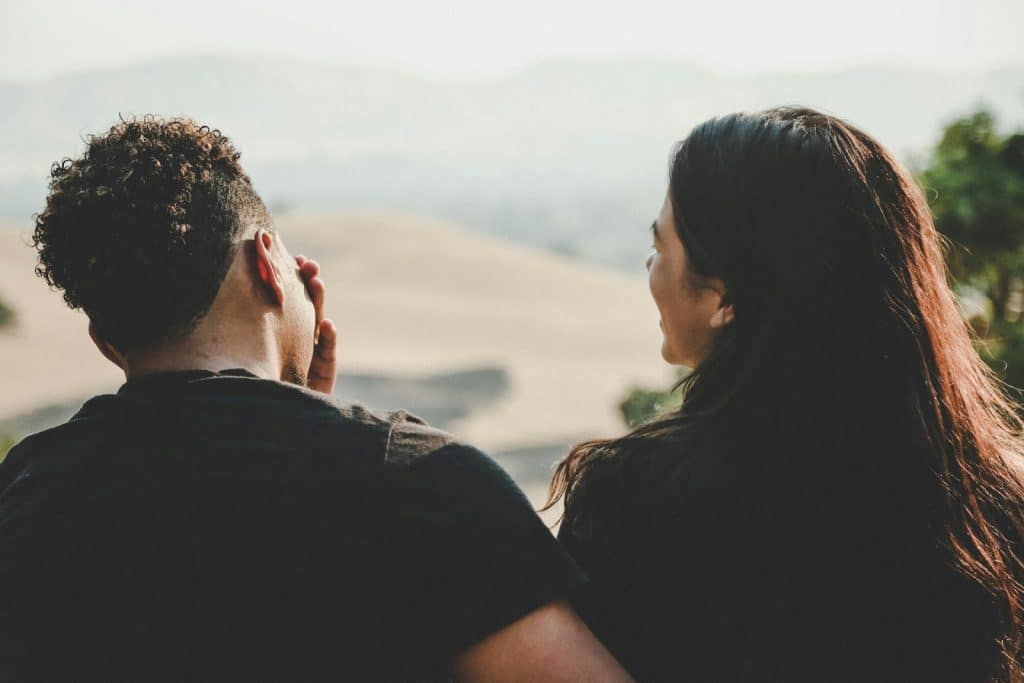 The couple is laughing while talking outdoors.