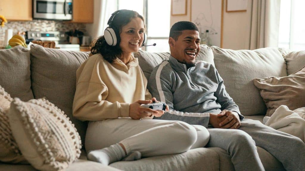 A couple sitting on a couch playing video games together.
