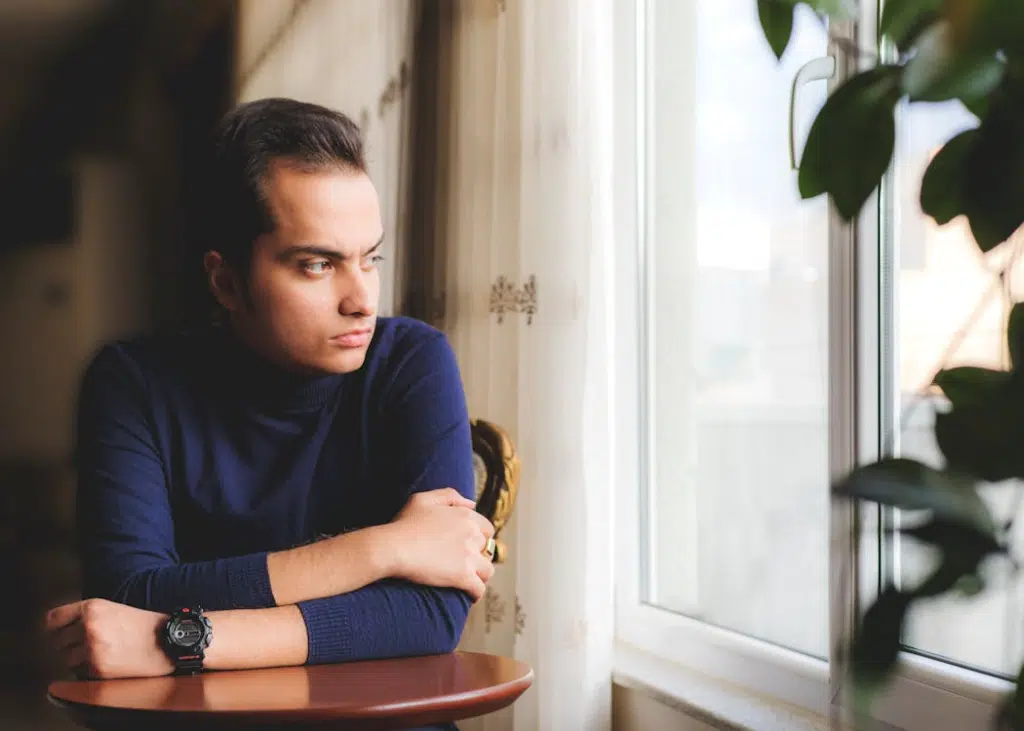 Man in Blue Sweater Looking Out the Window