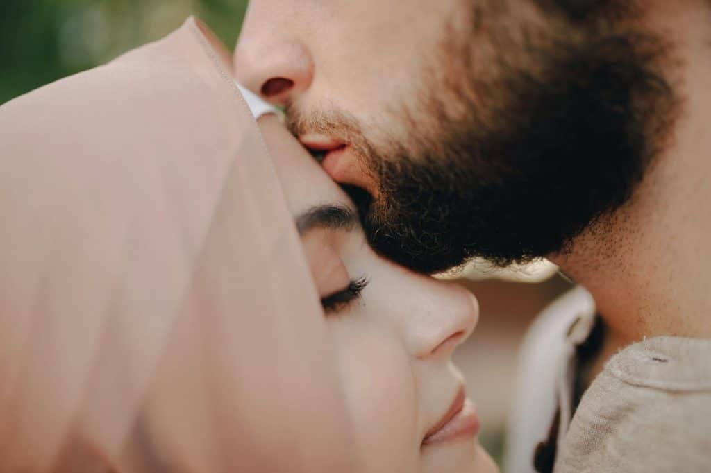 A man kissing a woman’s forehead