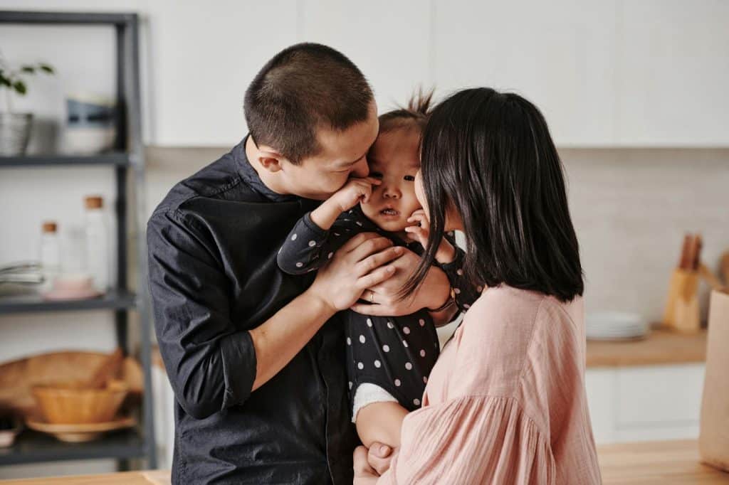 A man and woman kissing a baby