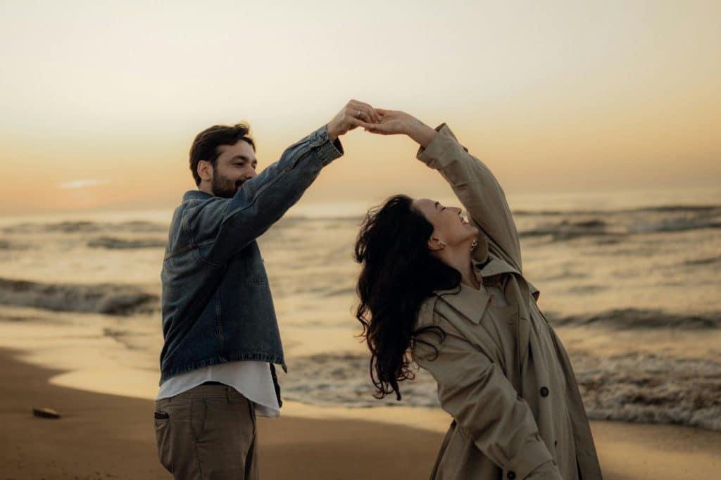 A man and woman dancing at the beach