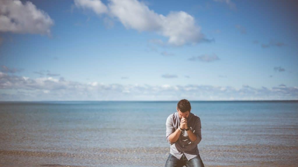 Man kneeling down near seashore.