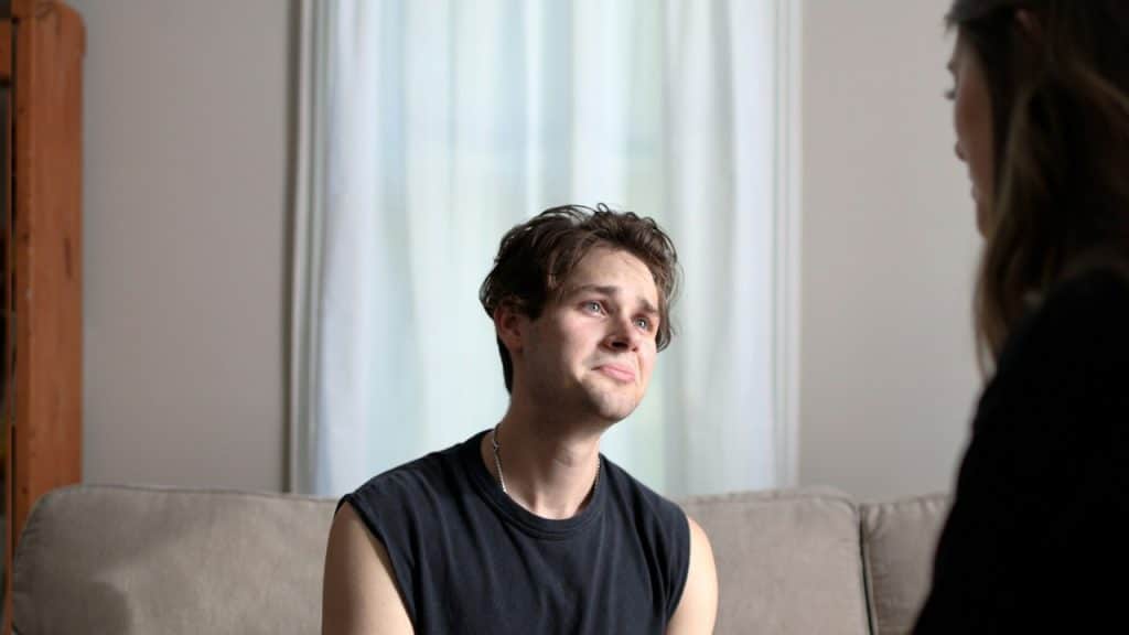 A man sitting on a couch talking to a woman.