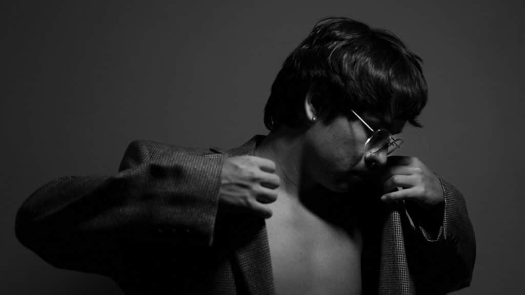 A man in a jacket posing with a bare chest.