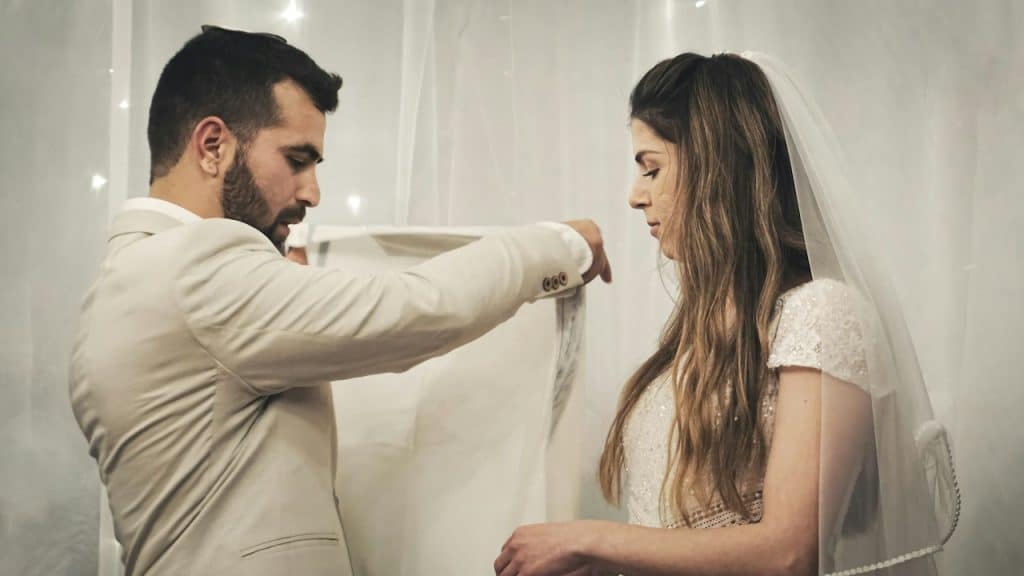 A man fixing the dress of his bride.