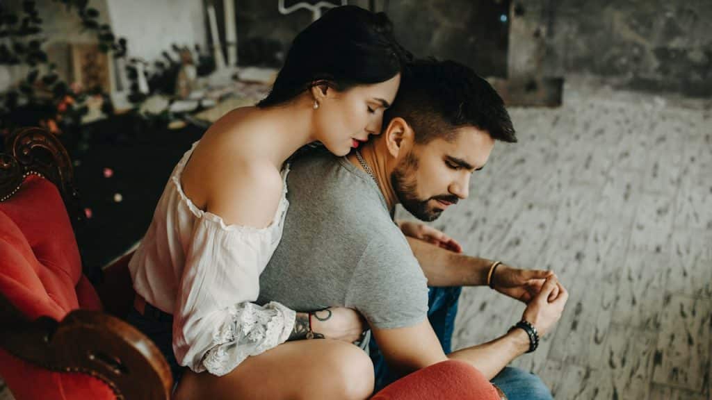 A couple sitting on a vintage red chair.