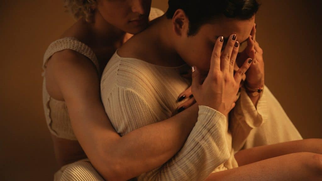 A sad man in the lap of a woman.