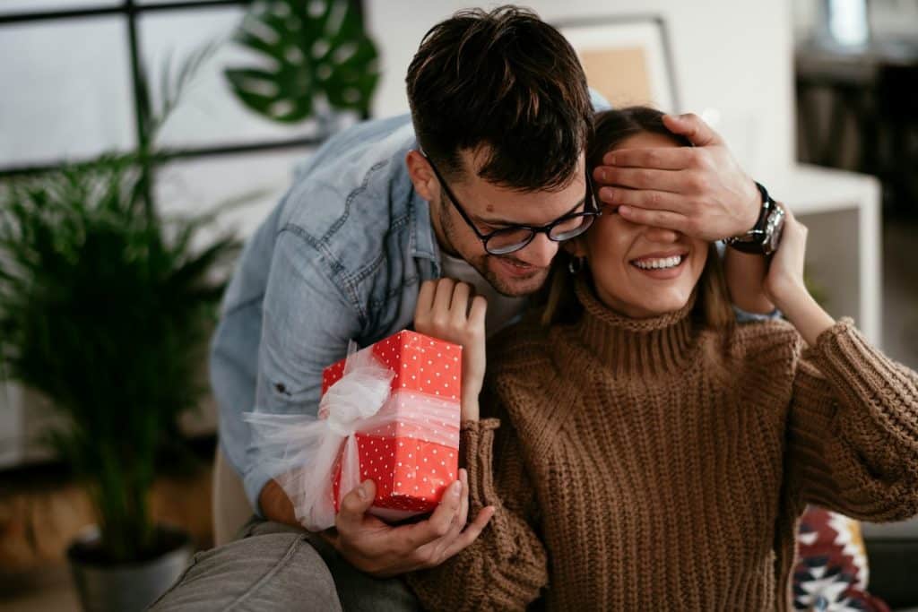 The man is surprising the woman with a gift.