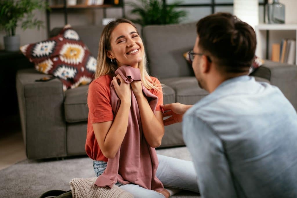 The woman is smiling while holding the shirt.