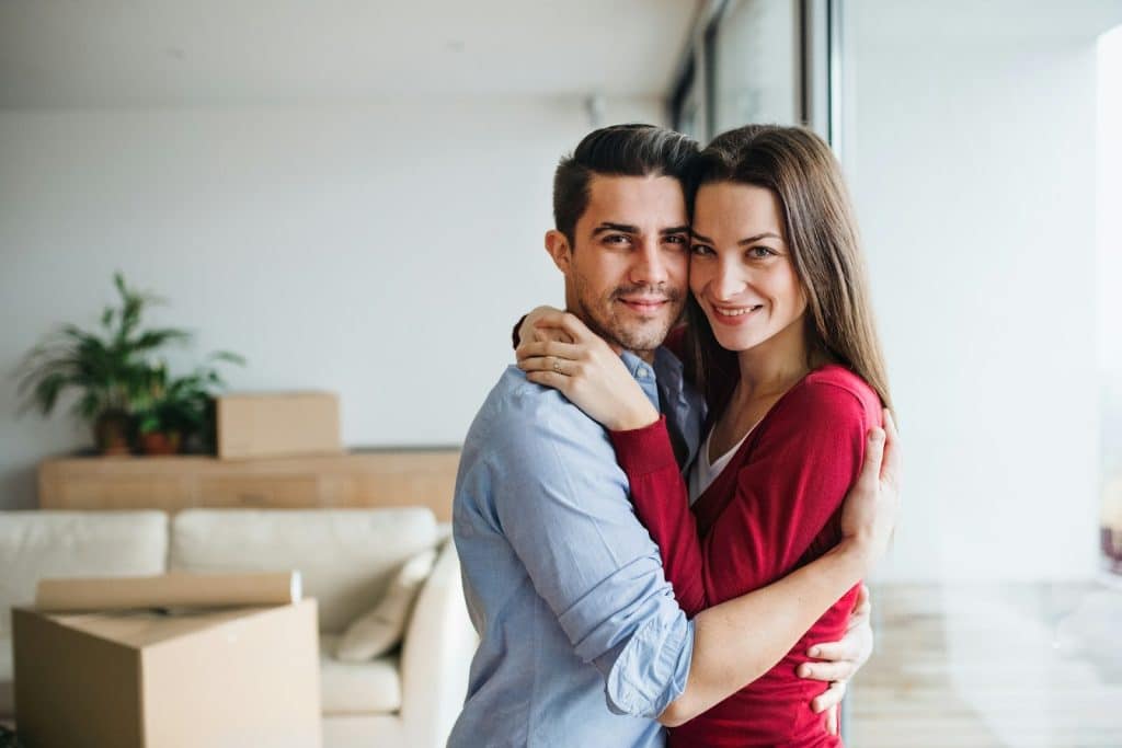 The couple is embracing each other in the living room.