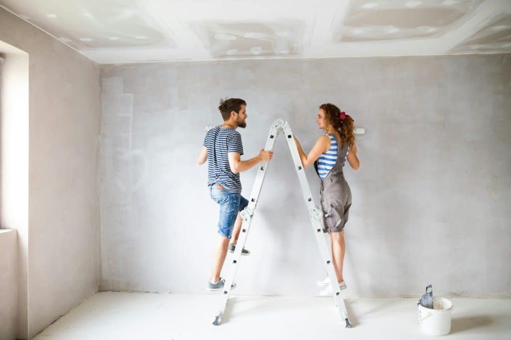 The husband is helping her wife paint the walls.