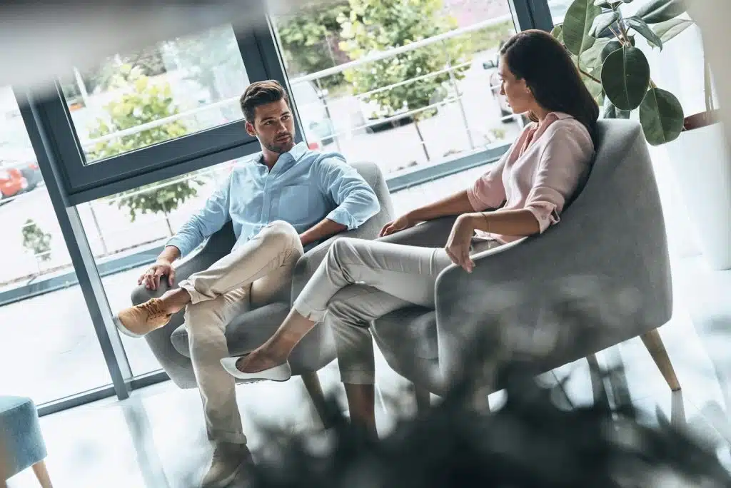 The couple is sitting beside each other indoors.