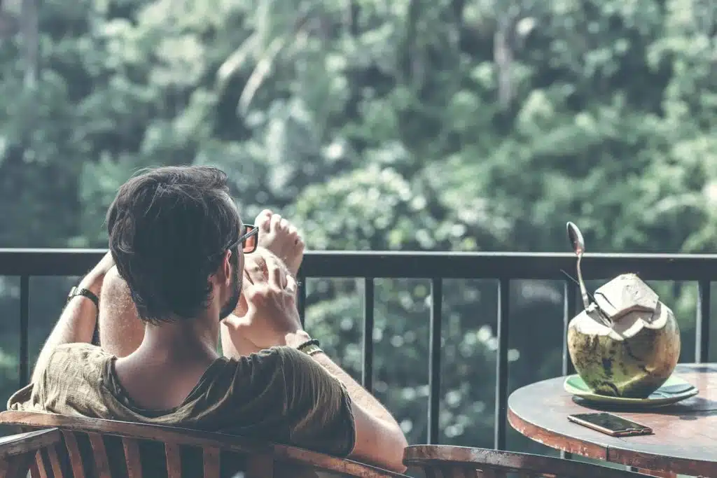 The man is sitting beside a table with an opened coconut on it.