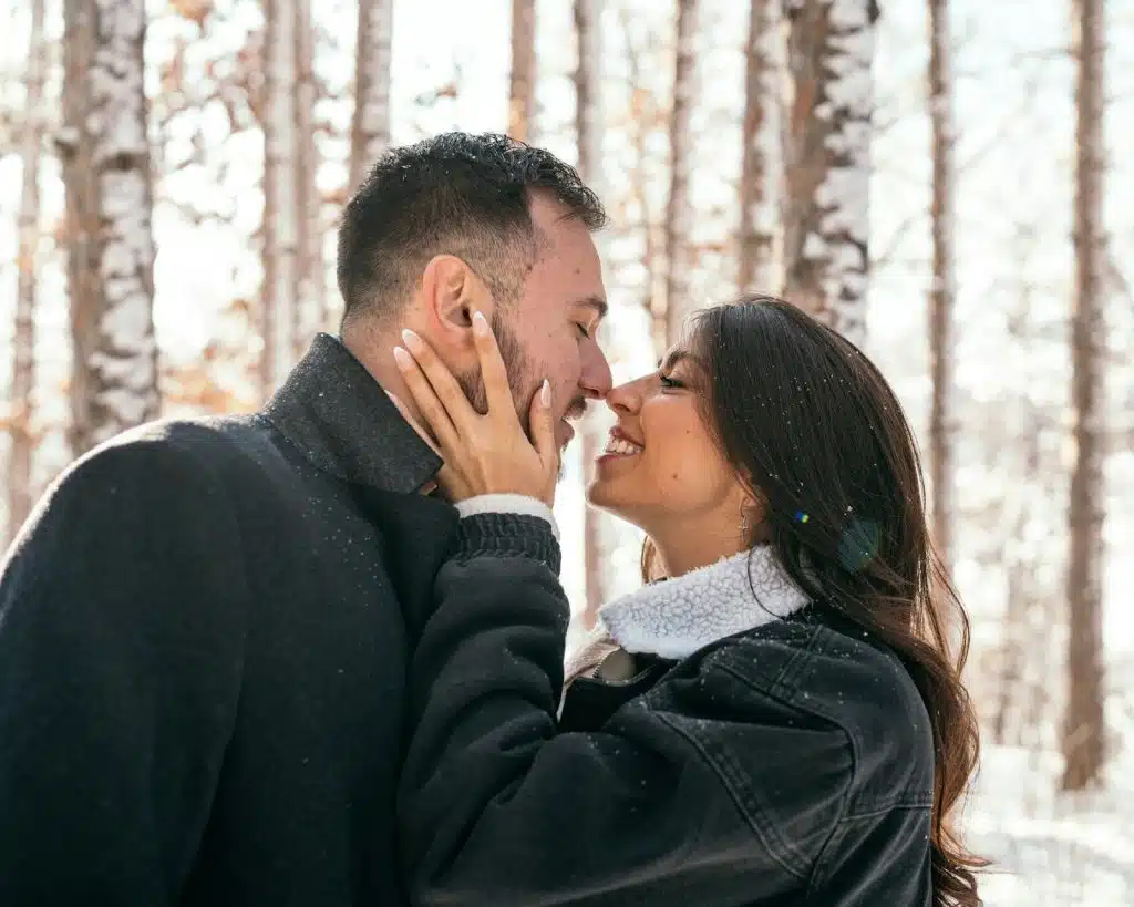The man and woman are kissing on the snow.