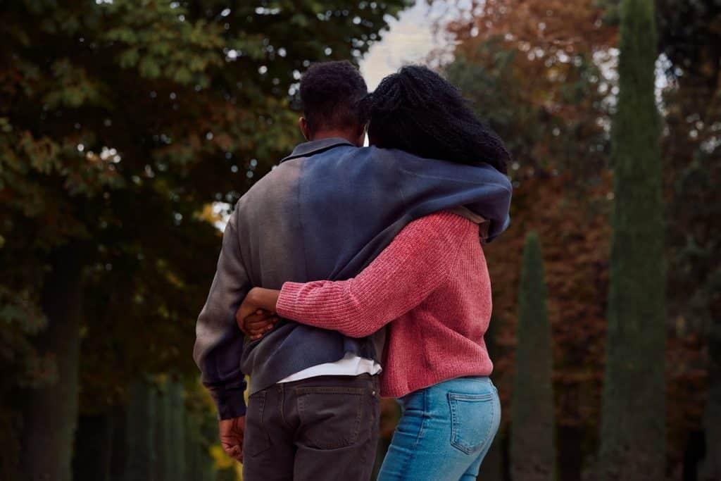 The woman in the pink sweater is hugging the man.