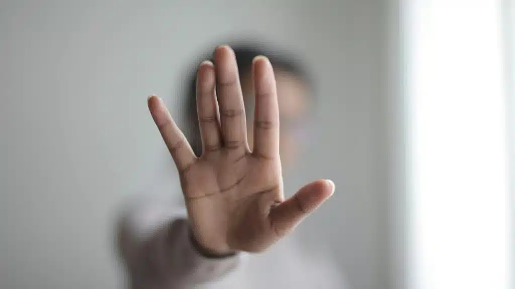 A person holding up their hand as if to signal stop.