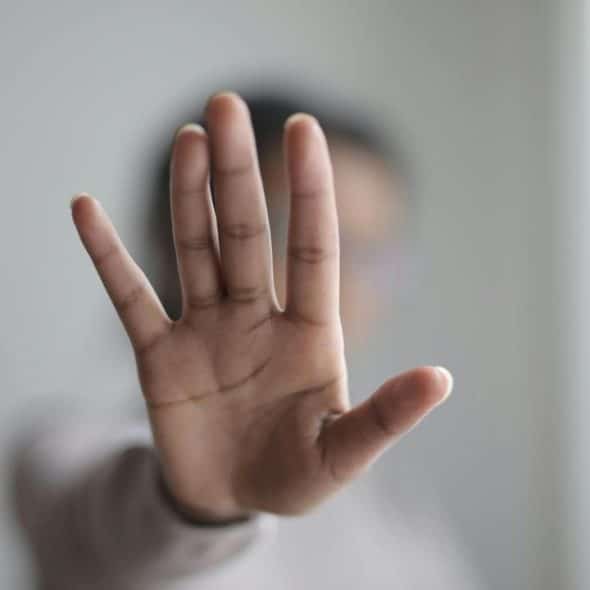 A person holding up their hand as if to signal stop.