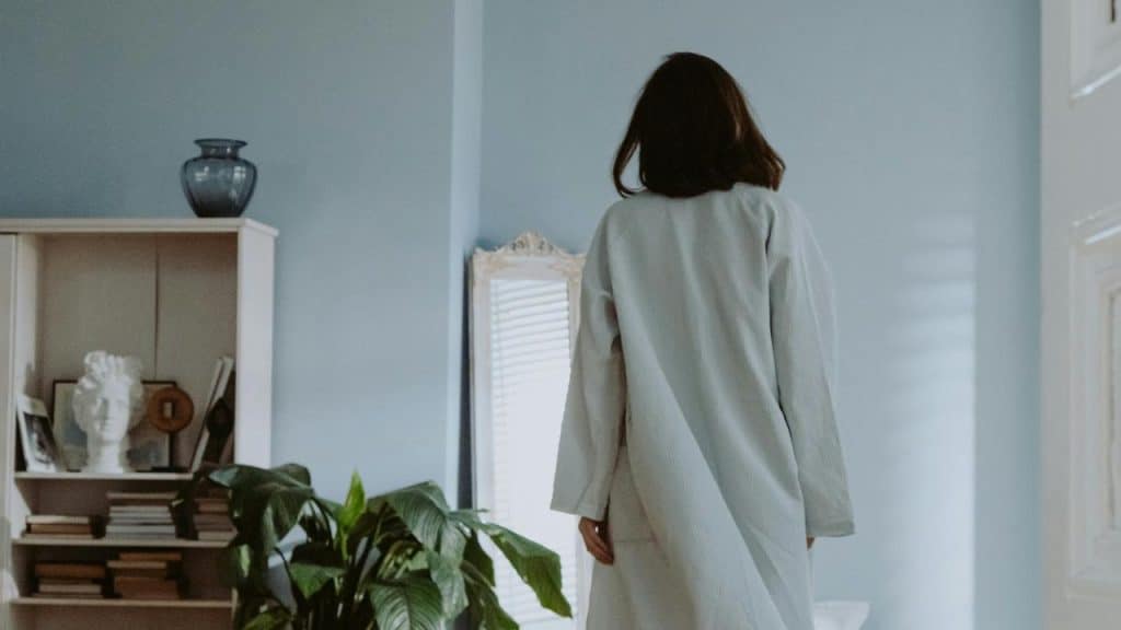A person standing in a room facing away from the camera.