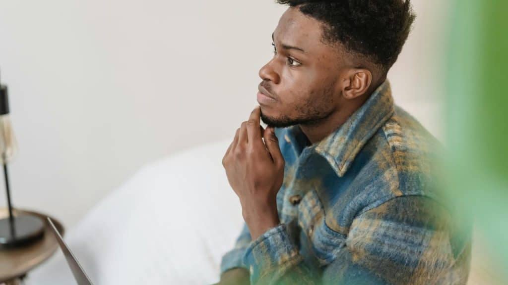 A person sitting and resting their hand on their chin, appearing thoughtful.