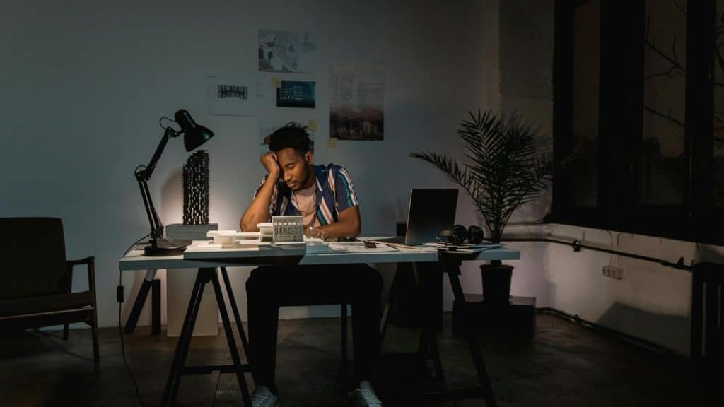 A person sitting at a desk late at night, looking tired or stressed.