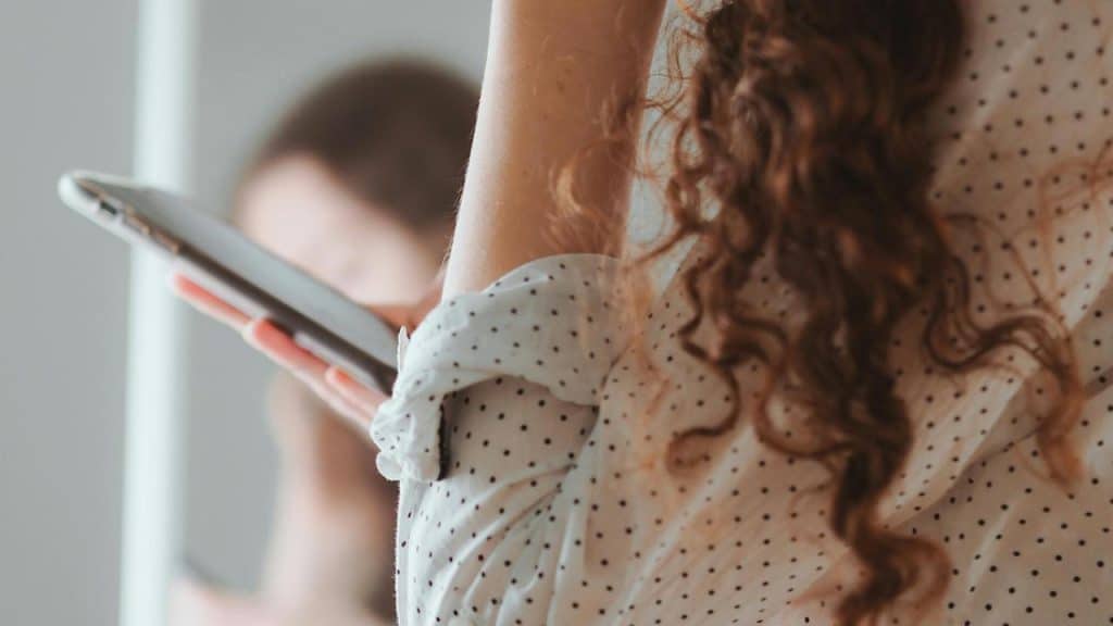 A person holding a tablet while another is blurred in the background.