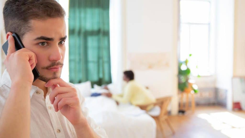 A person talking on the phone while another sits in the background.