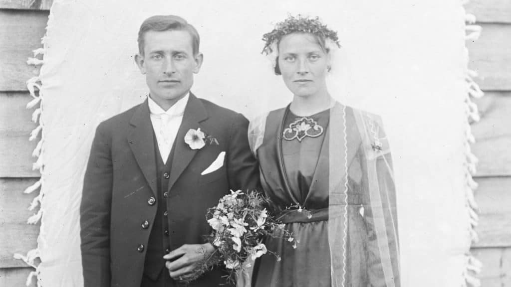 A black and white photo of a man and woman in wedding attire standing side-by-side.