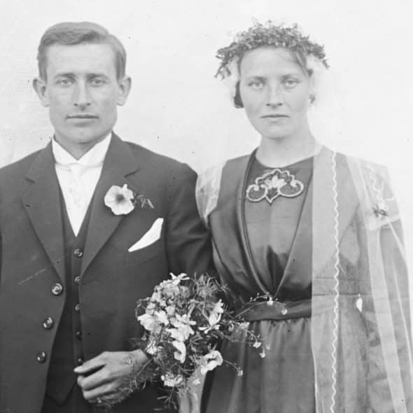 A black and white photo of a man and woman in wedding attire standing side-by-side.