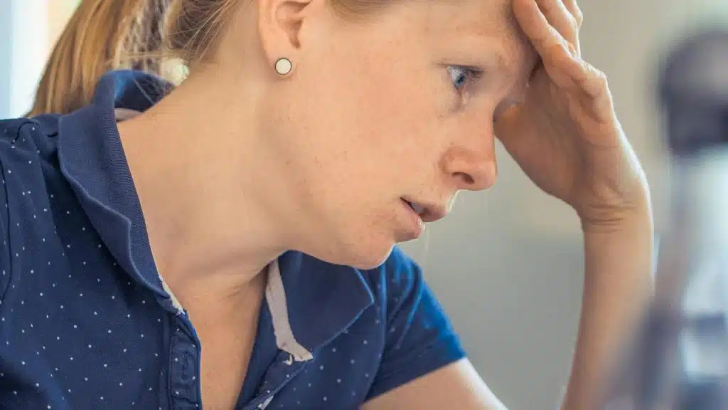 A woman holding her head with a stressed expression.
