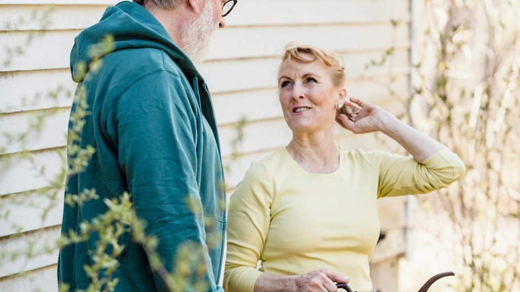 A senior couple talking together outdoors near a house.