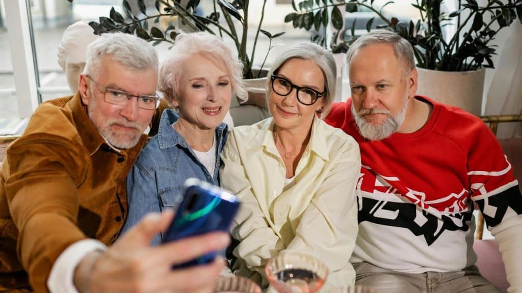 A group of older friends sitting together taking a selfie.