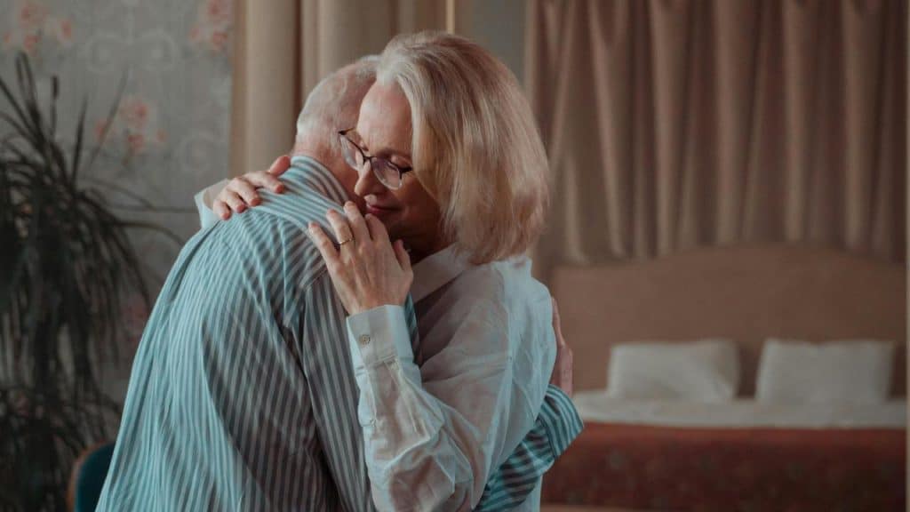 A senior couple hugging warmly in a cozy room.
